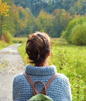 Weibliche Person mit Rucksack auf einem Waldweg